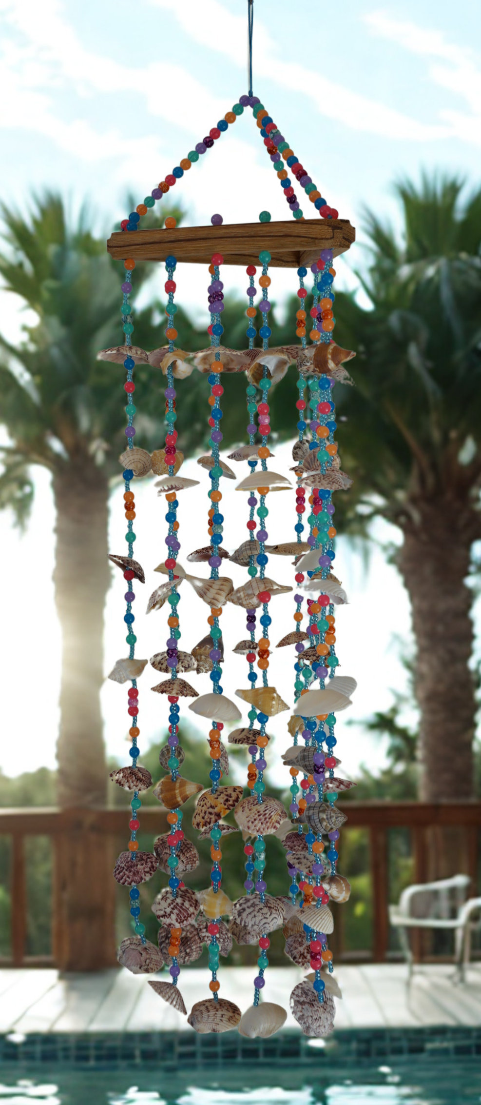 Colorful wind chime with seashells and beads against a blurred outdoor background