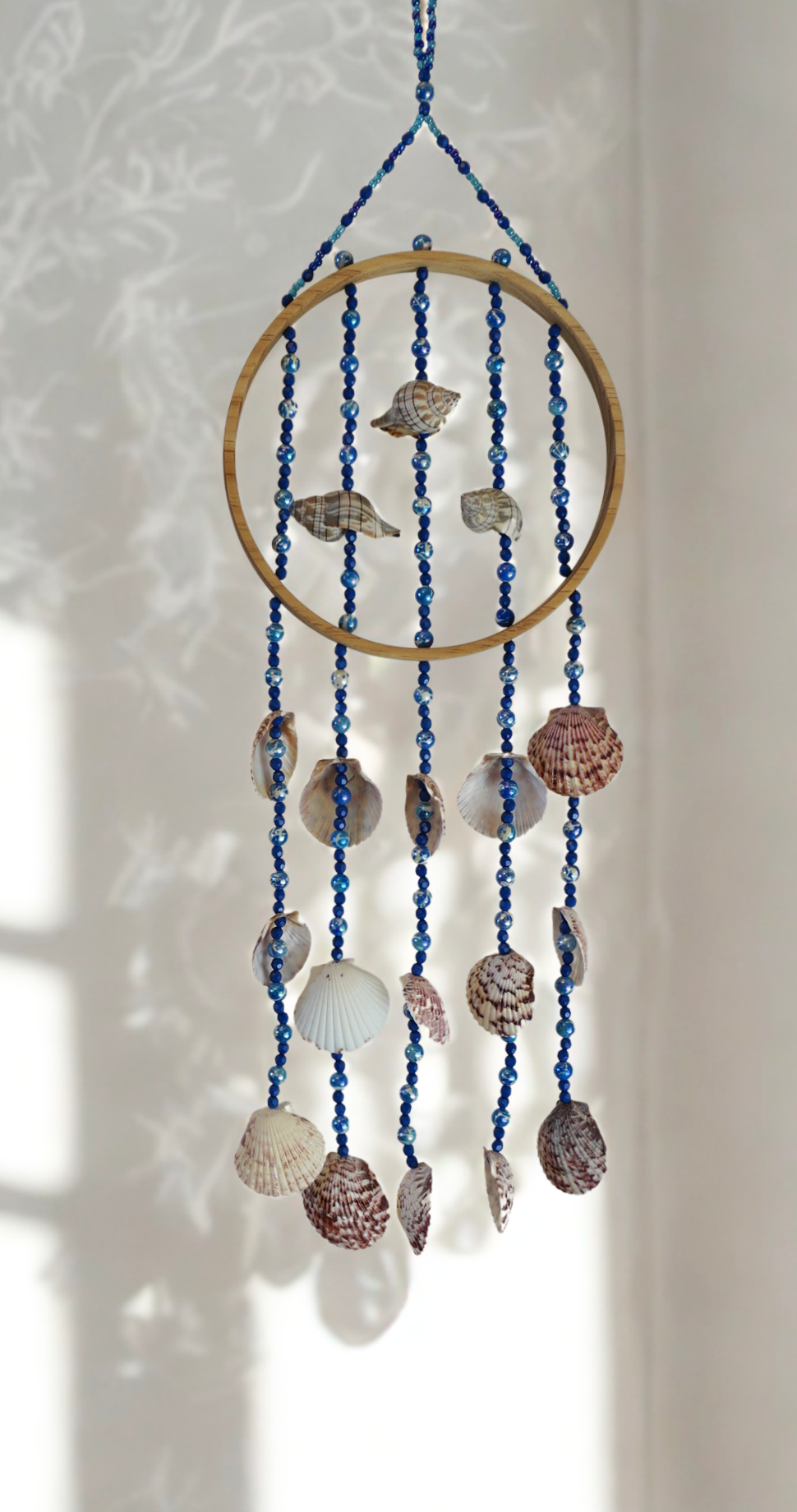 Decorative wall hanging with shells and beads on a white background