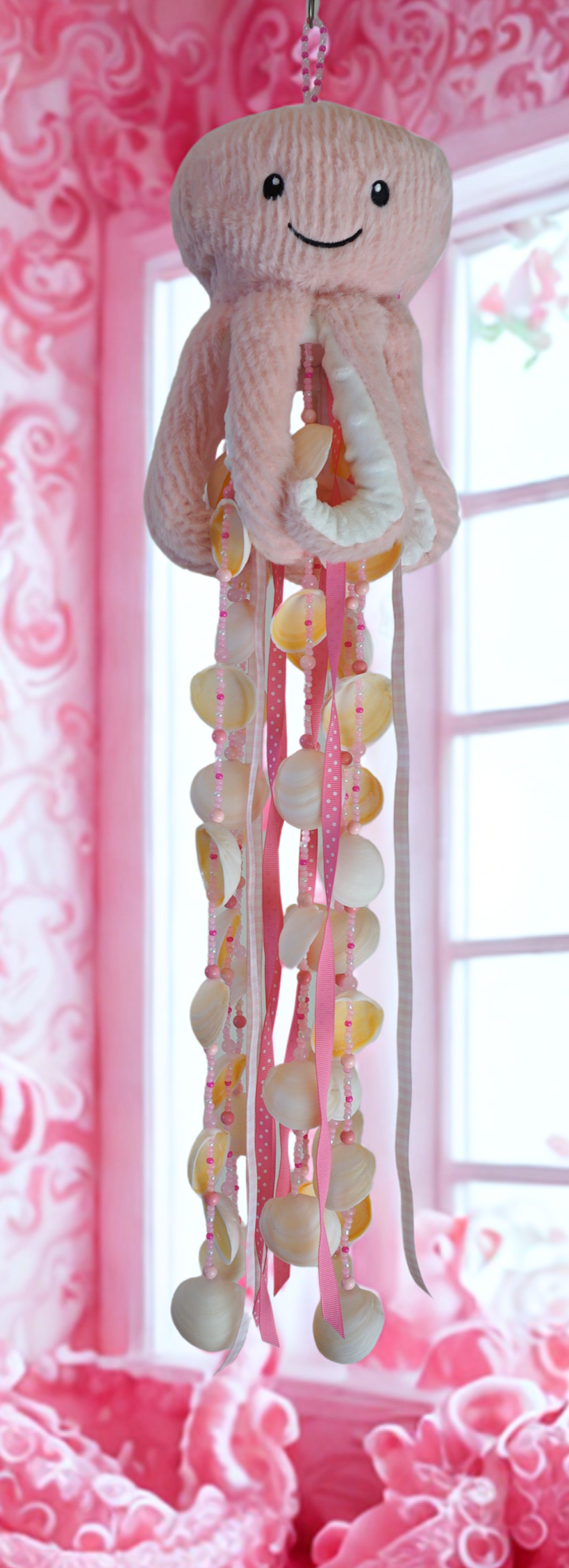 Jellyfish wind chime with seashells hanging against a pink floral background