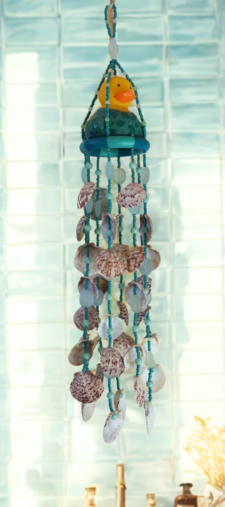 Decorative shell wind chime with a rubber duck and seashells against a light background