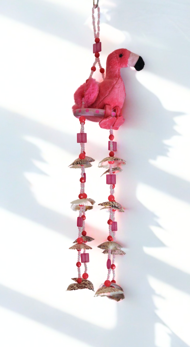 Pink flamingo wind chime with beads and shells on a white background