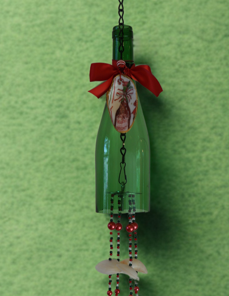 Decorative hanging bottle wind chime with shells, beads and a red bow on a green background