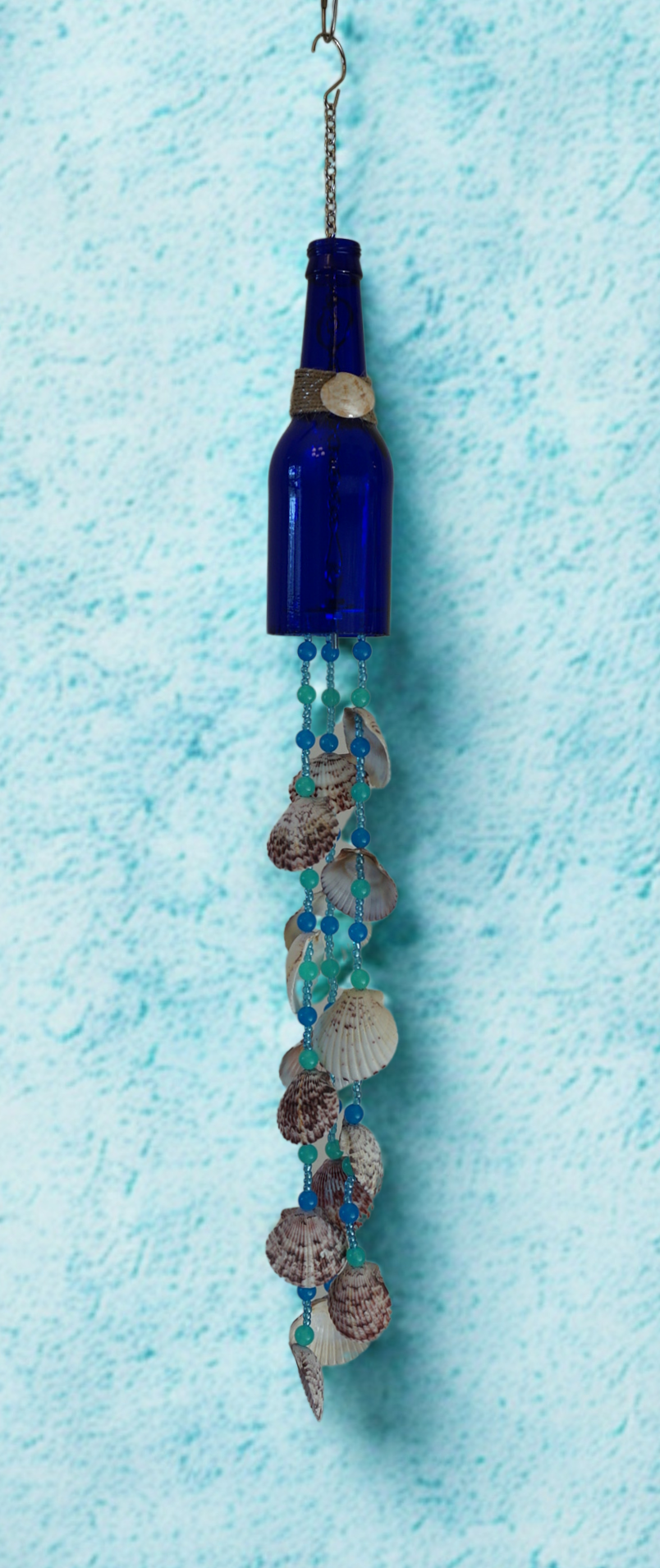 Decorative bottle wind chime with seashells and beads on a blue textured background
