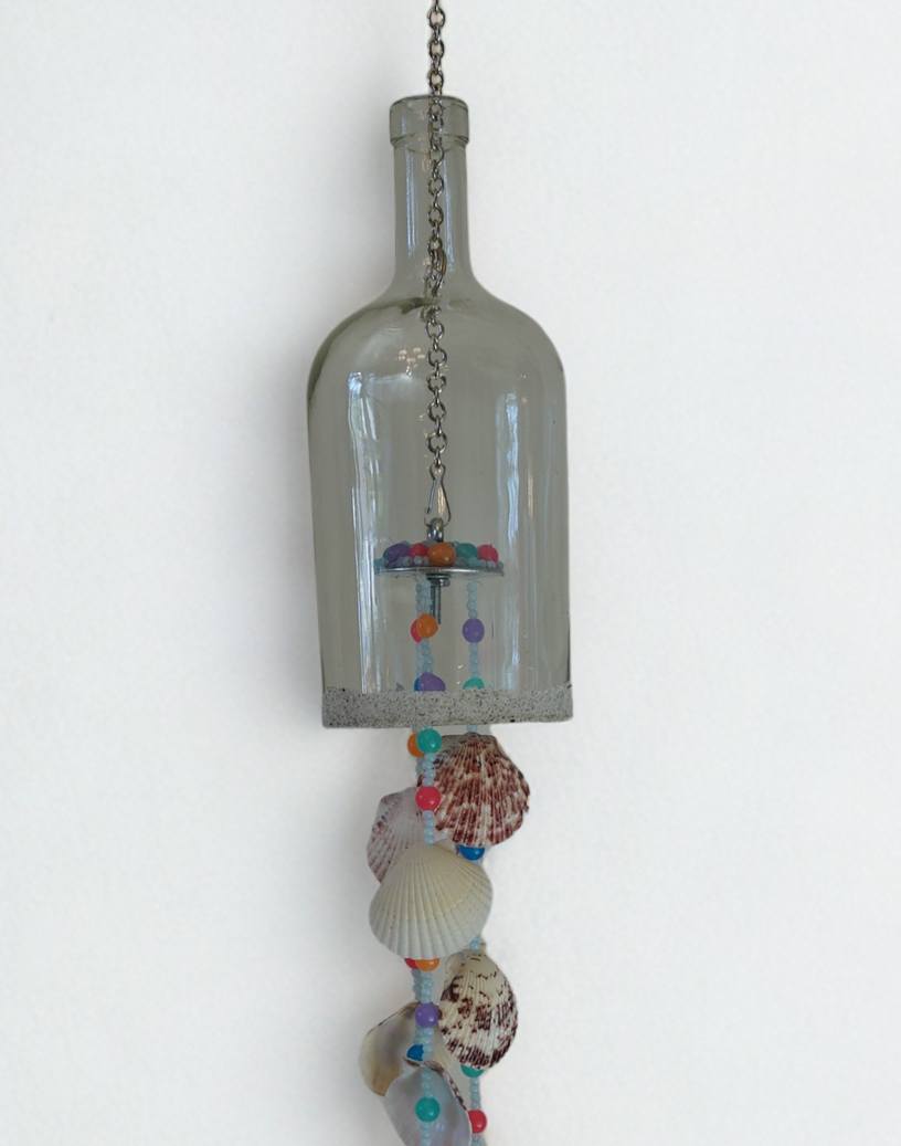 Decorative hanging bottle wind chime with seashells and beads on a white background