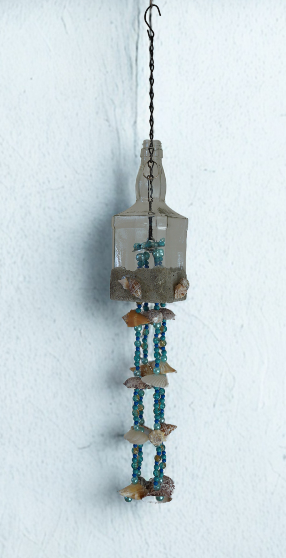 Decorative wind chime hanging bottle with seashells and beads on a white background