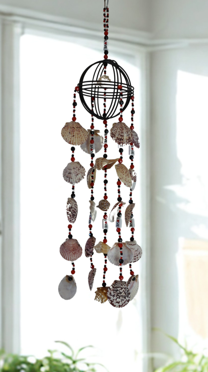 Decorative wind chime with shell and bead elements hanging against a bright window.