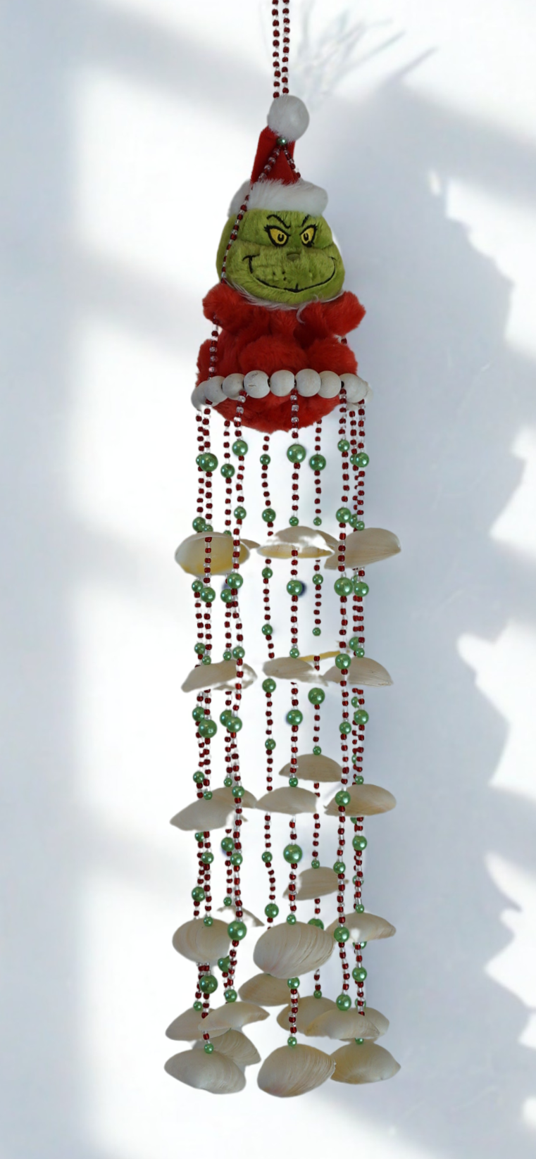 Decorative hanging wind chime with a character and shell beads on a white background