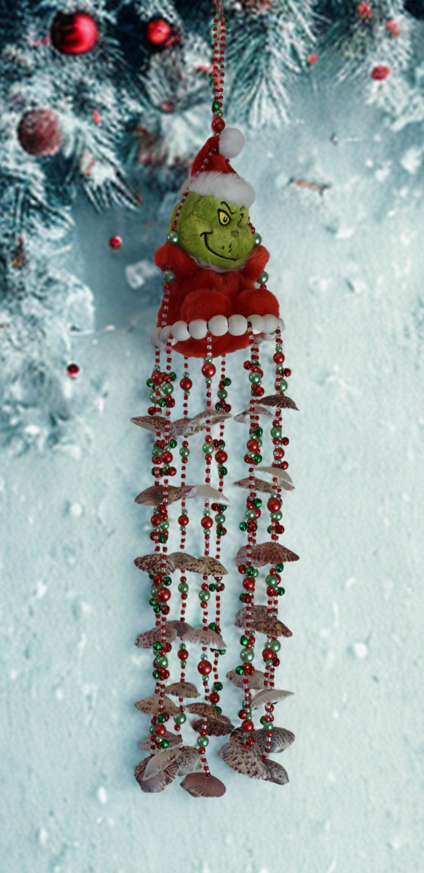Decorative hanging wind chime with shells and plush character on a snowy background