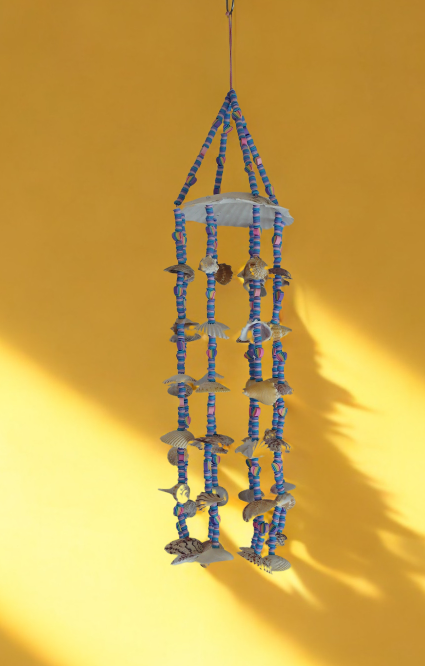 Decorative scallop shell top wind chime with blue and pink beads on a yellow background