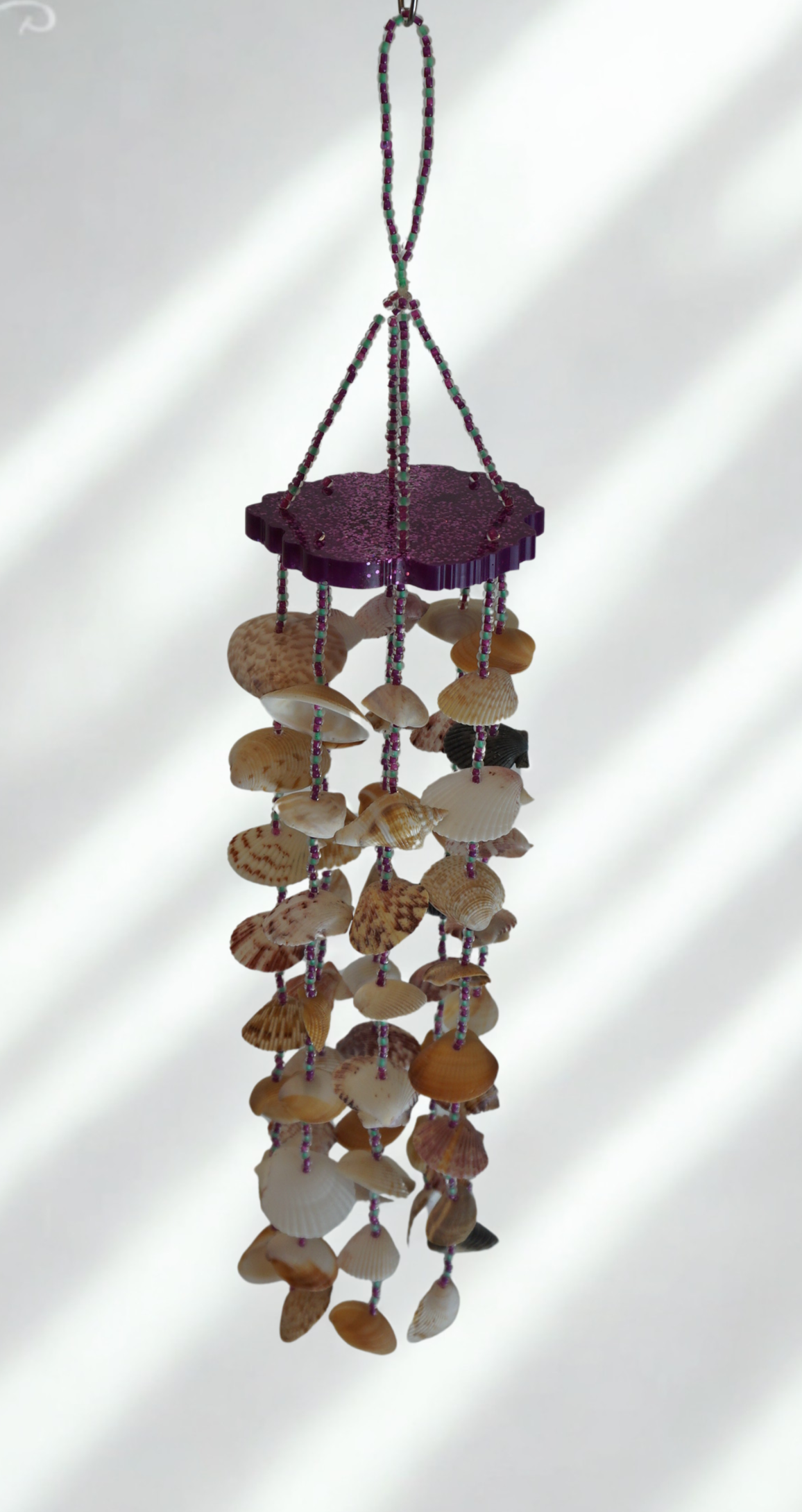 Shell wind chime hanging against a white background