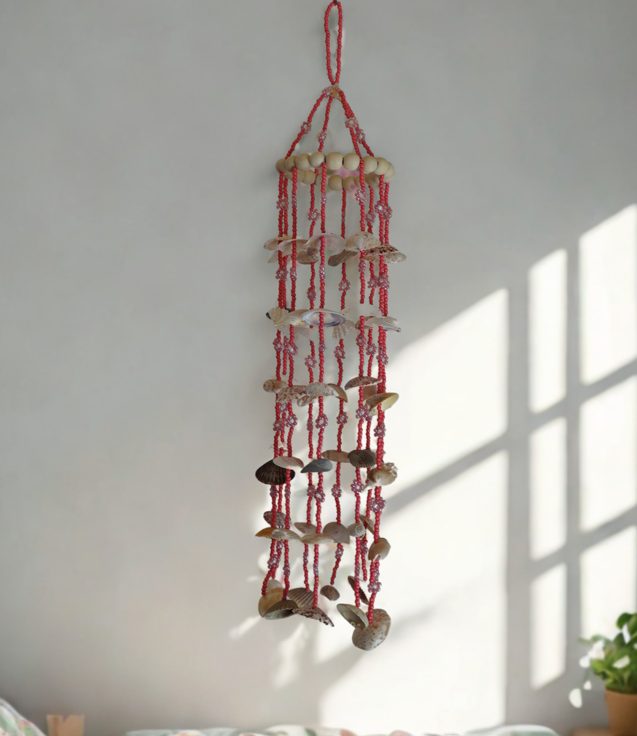 Wood bead and shell wind chime on a wall near a window