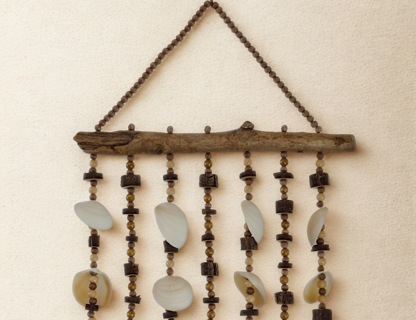 Decorative wall hanging with beads, natural wood elements and shells on a beige background