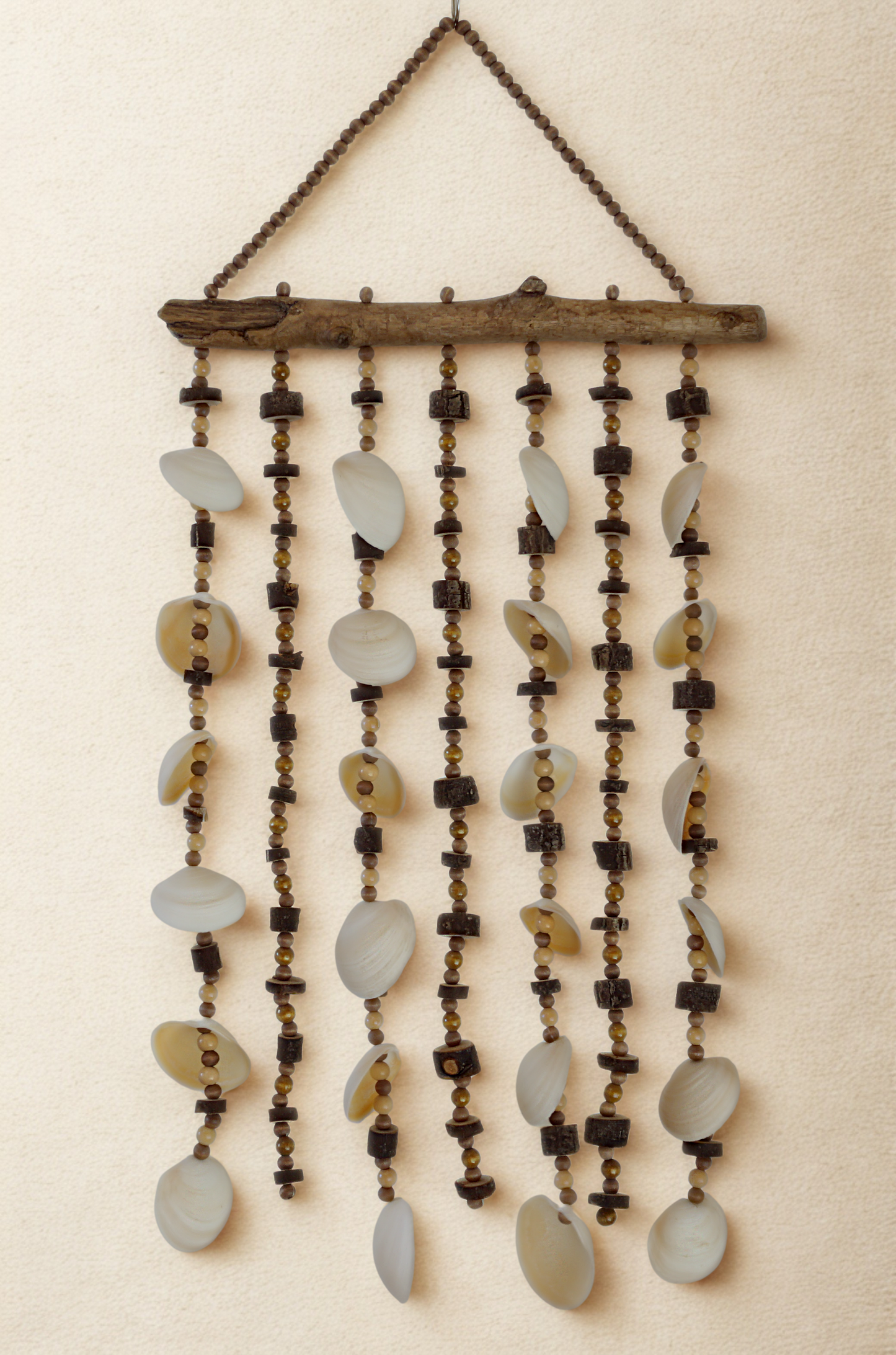 Decorative wall hanging with shells, beads, wood on a beige background