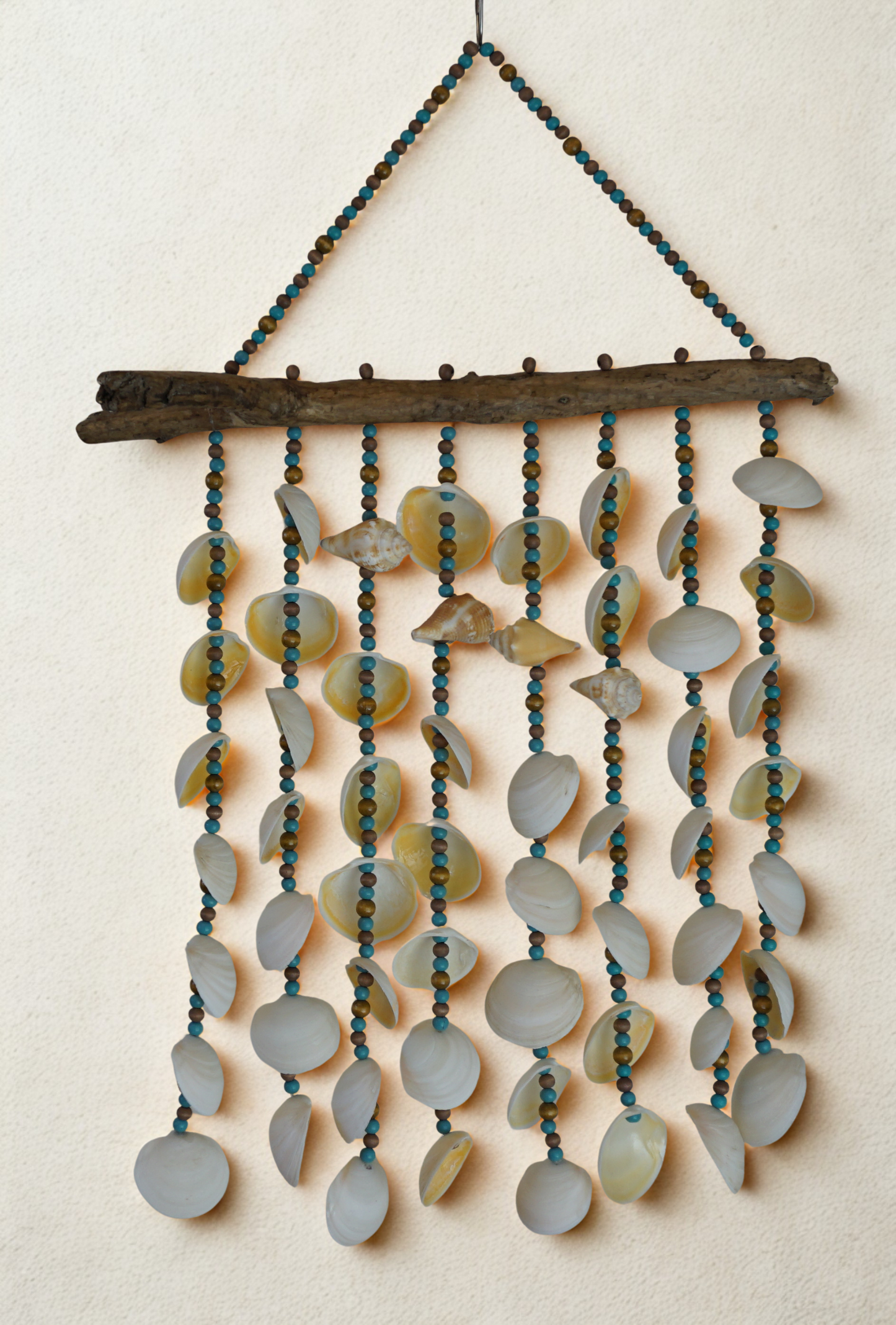 Decorative wall hanging with shells and beads on a neutral background