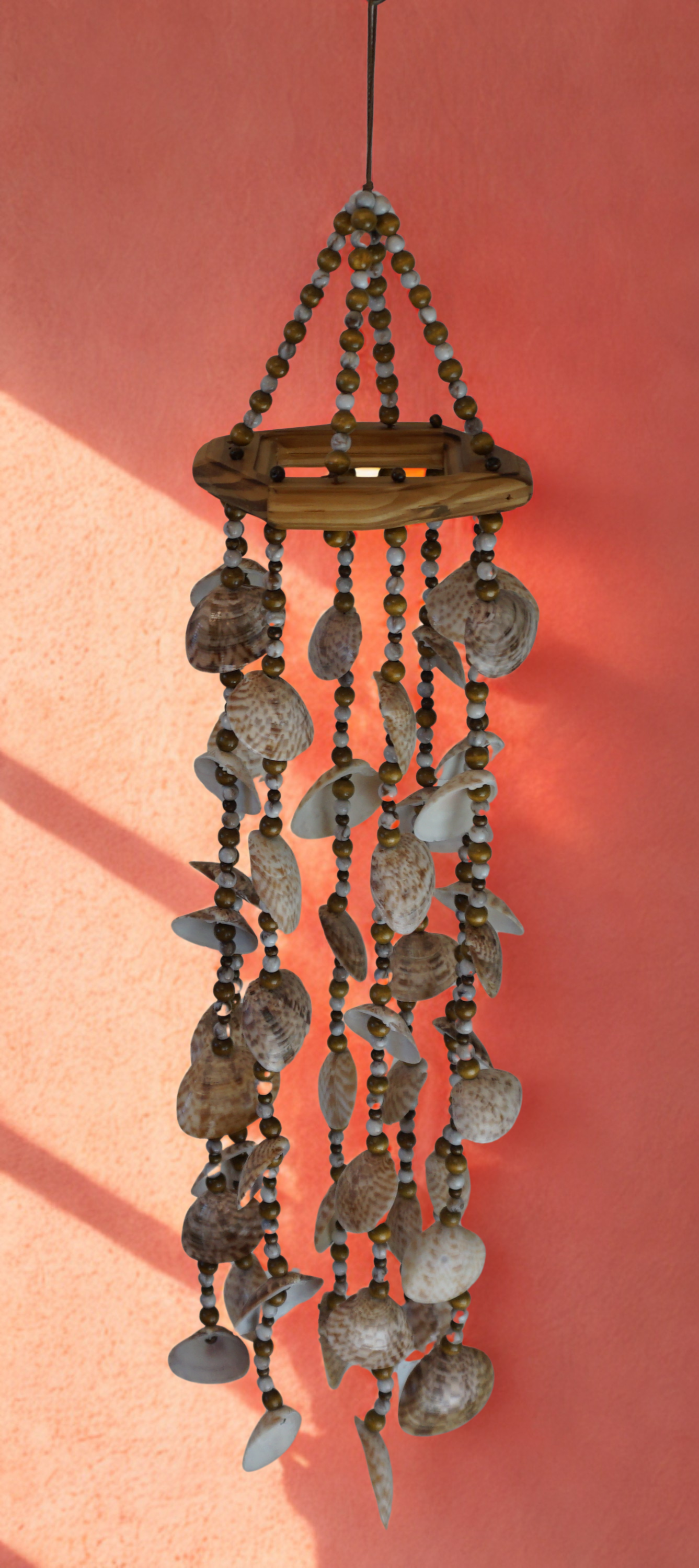 Decorative shell wind chime against a pink background