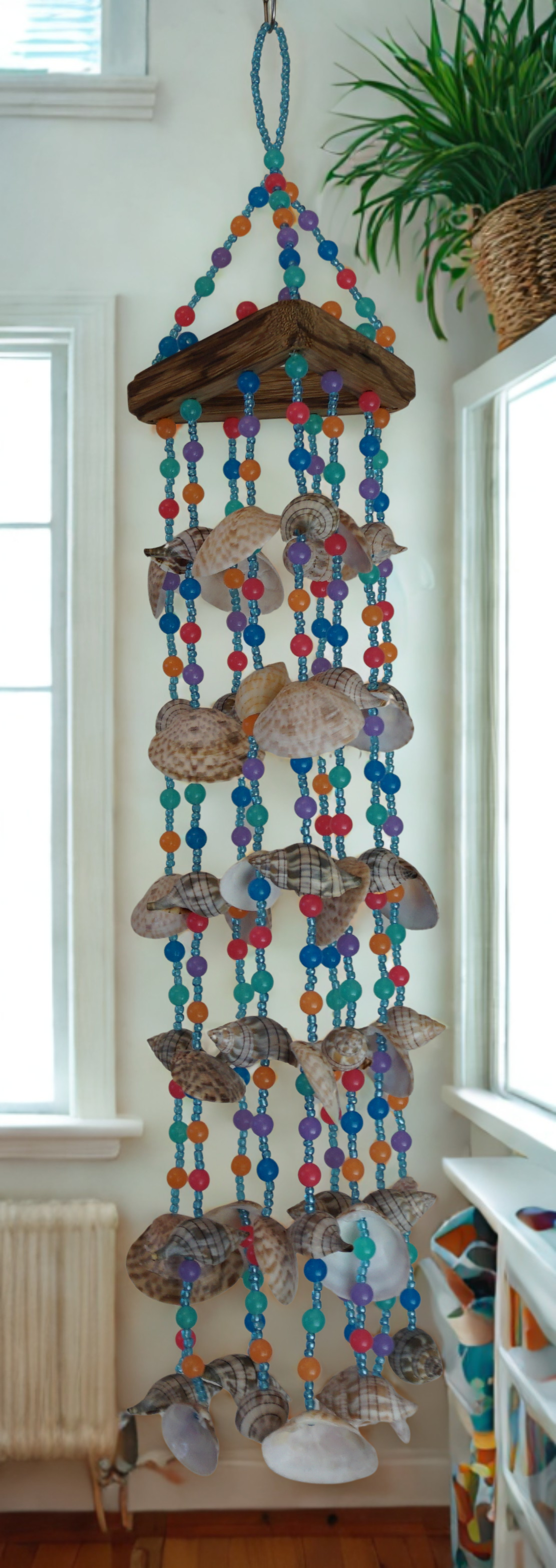 Decorative wind chime with colorful beads and shells hanging indoors.