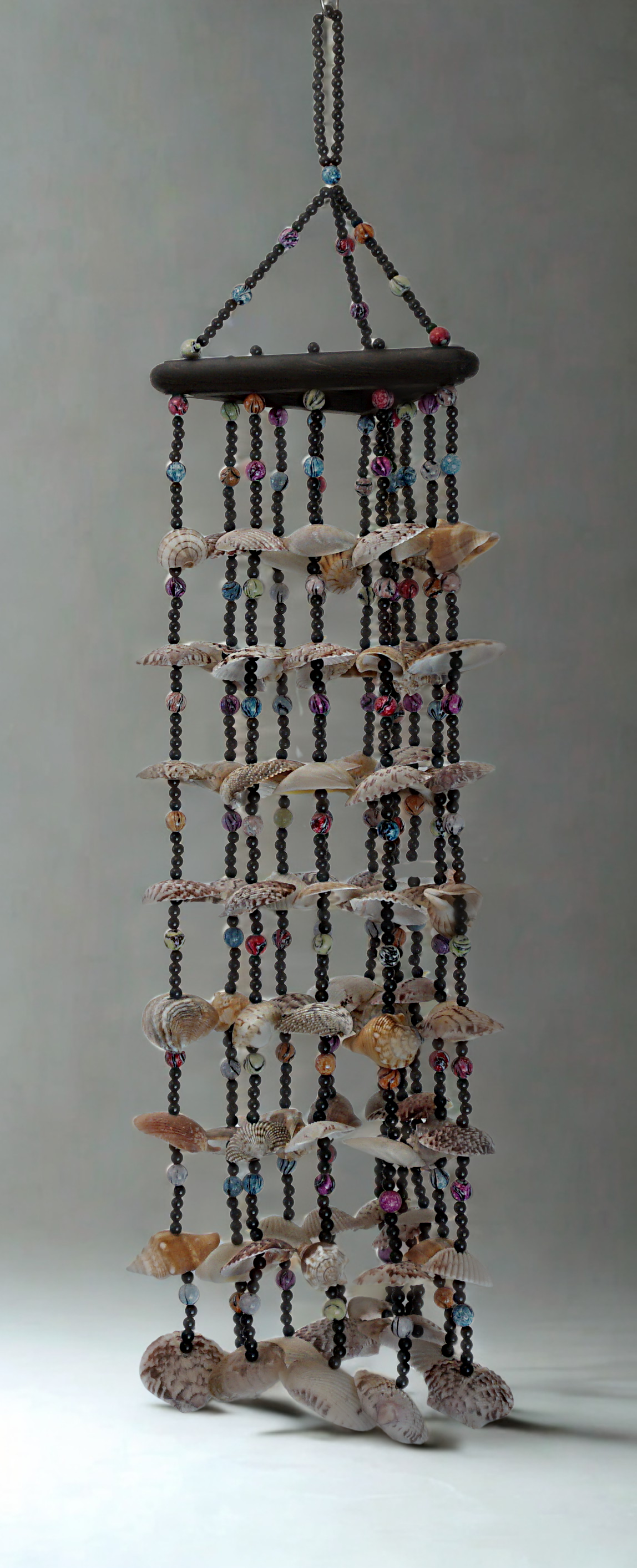 Decorative wind chime with shells and beads on a gray background