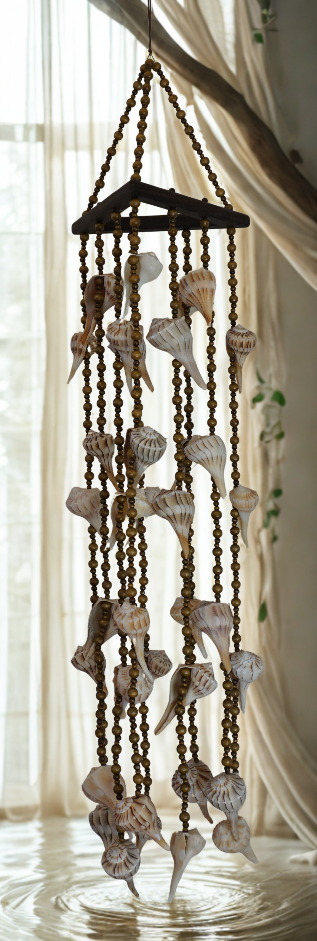 Decorative wind chime with shells hanging against a light curtain background