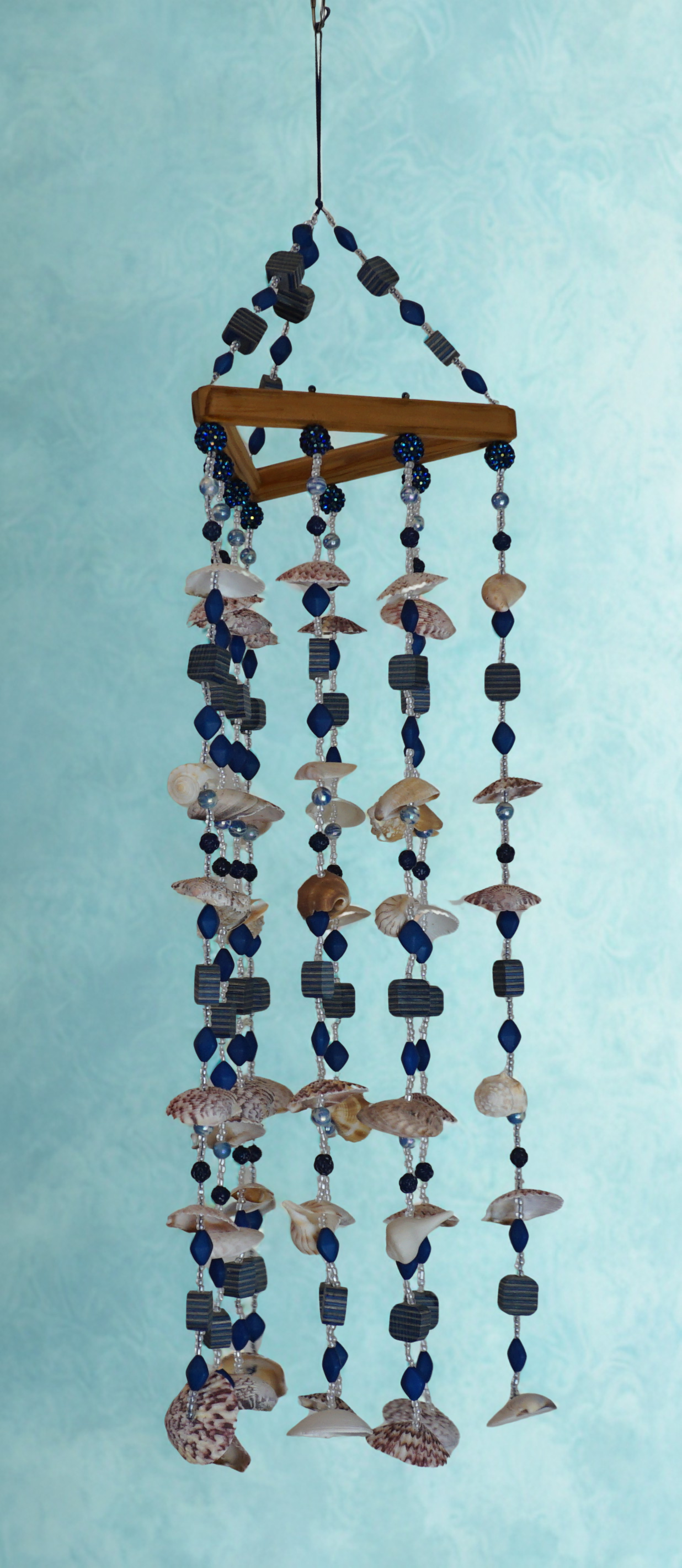 Decorative wind chime with seashells and beads on a light blue background