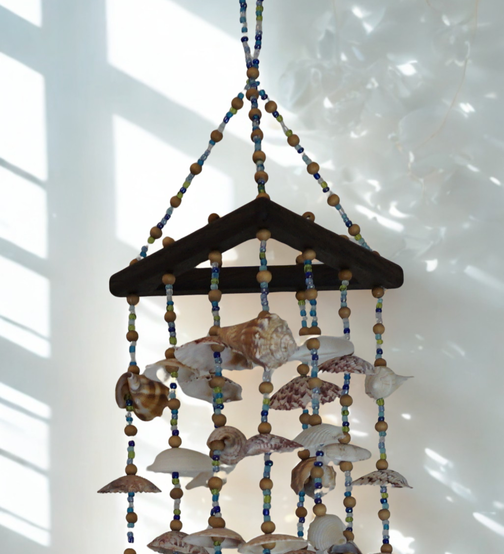 Decorative hanging wind chime made of seashells and beads on a white background
