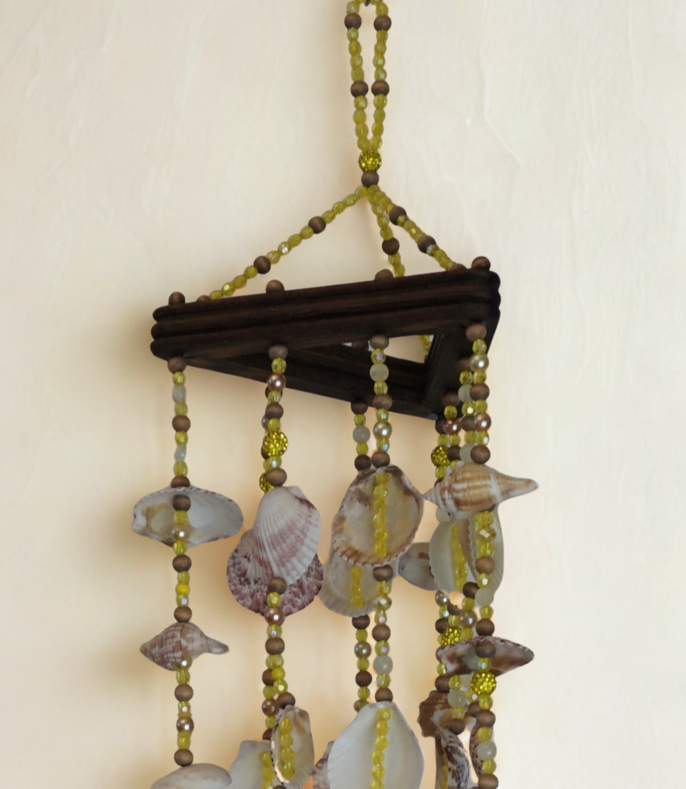 Decorative wind chime with seashells and beads on a plain background