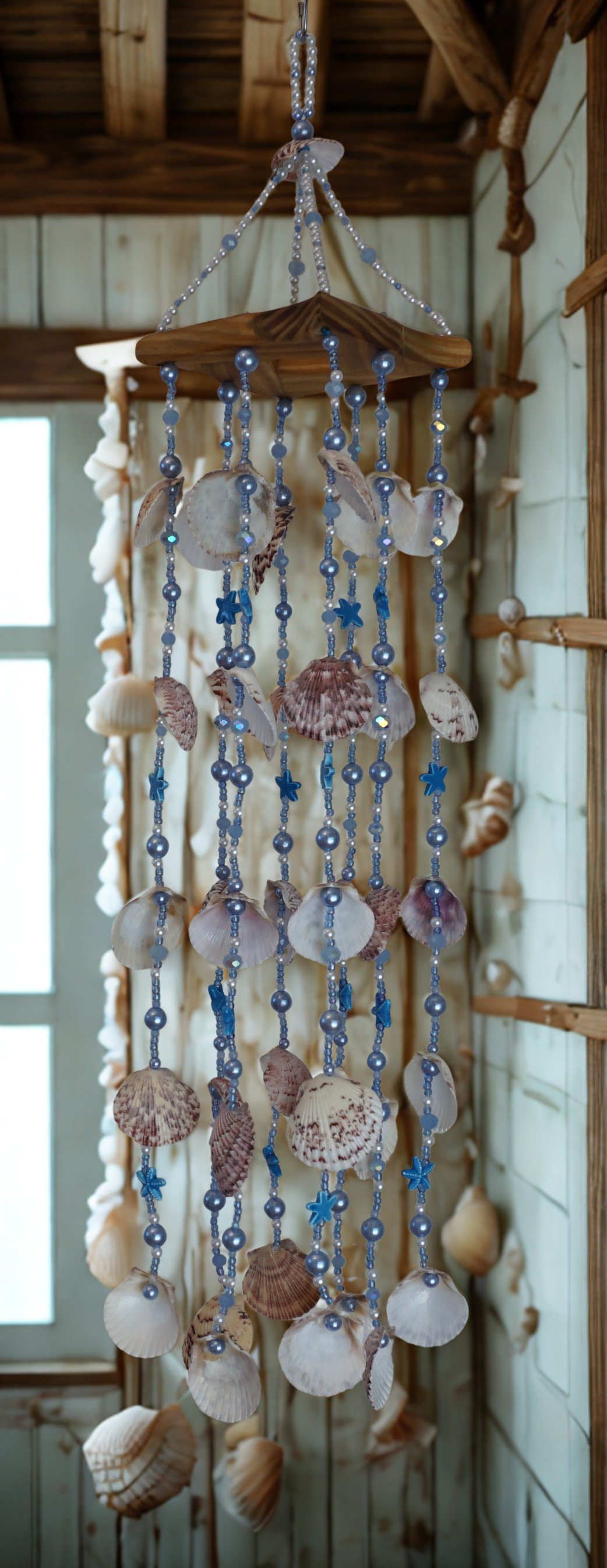 Decorative shell and bead wind chime hanging in front of a wall