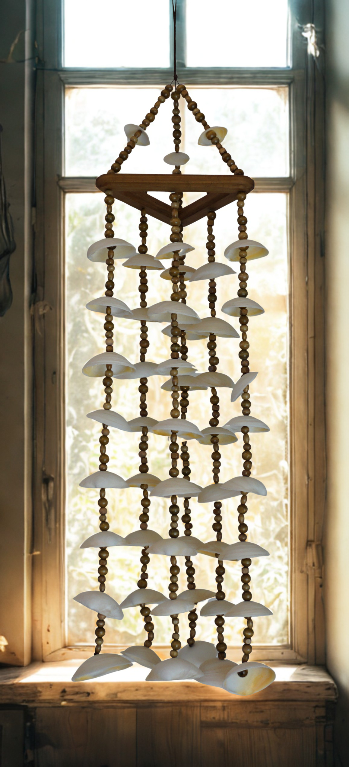 Decorative wind chime with shell and bead design in front of a window