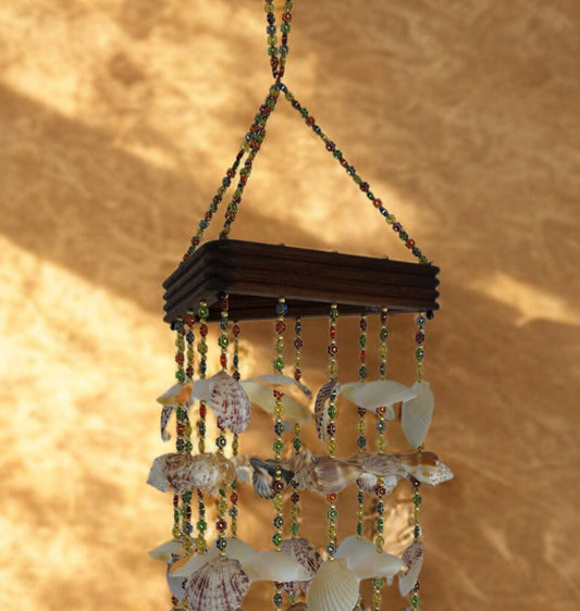 Decorative wind chime with seashells and beads against a beige background