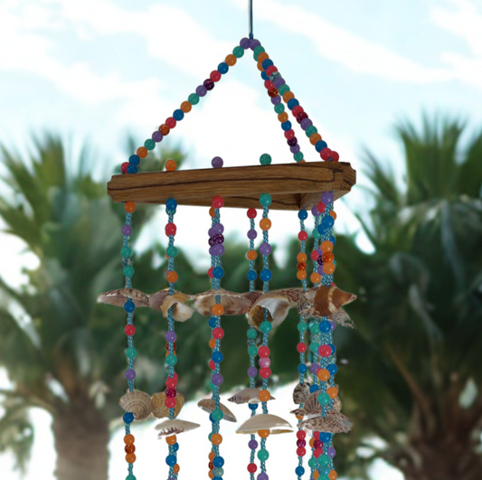 Colorful wind chime with seashells and beads against a blurred outdoor background