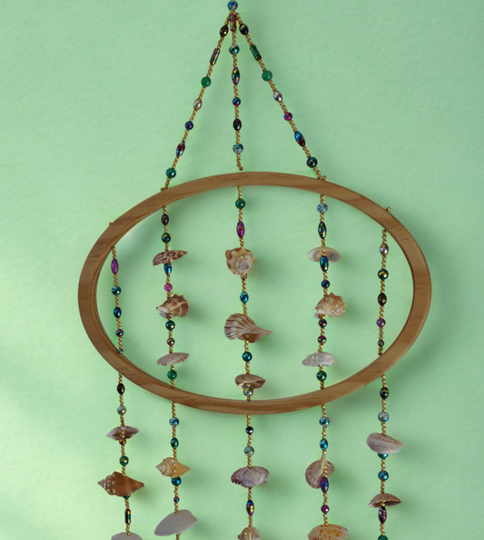 Decorative shell and bead wall hanging against a green background