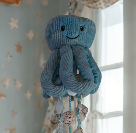 Decorative octopus wind chime with seashells hanging in a room with a window.