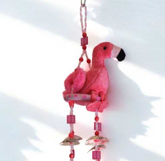 Pink flamingo wind chime with beads and shells on a white background