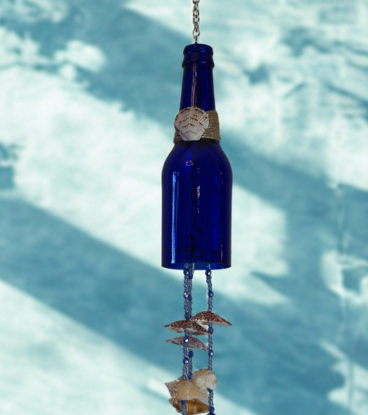 Blue glass bottle wind chime with decorative shell elements against a blue background