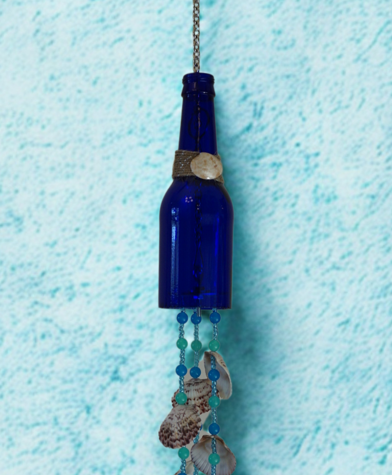 Blue bottle wind chime with beads and shells on a textured blue background