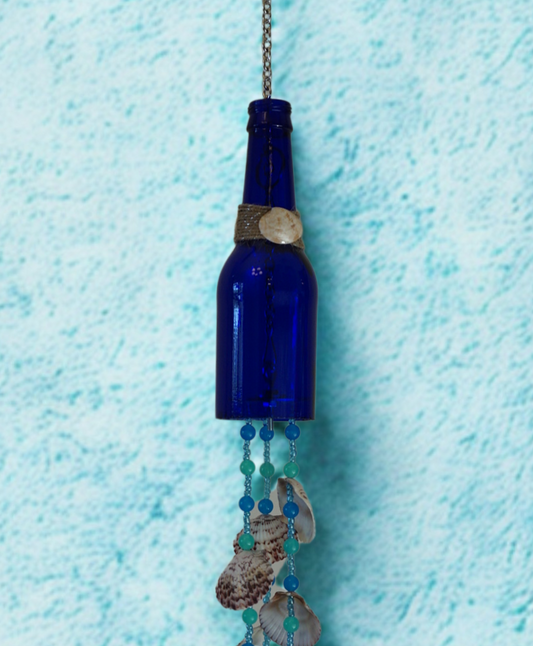 Blue bottle wind chime with beads and shells on a textured blue background