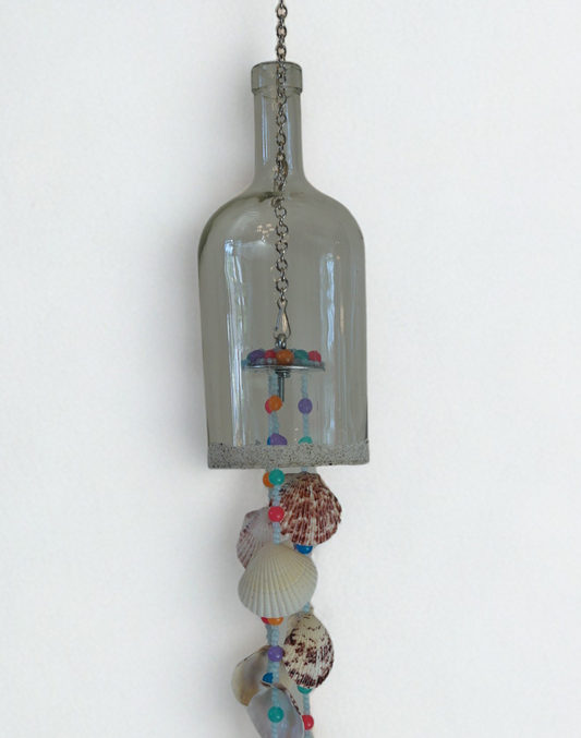 Decorative hanging bottle wind chime with seashells and beads on a white background