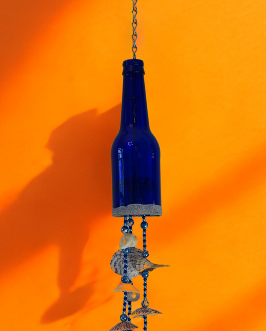 Blue glass bottle wind chime  with decorative shell elements against an orange background
