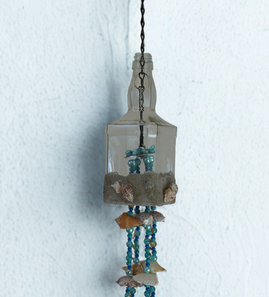 Decorative wind chime hanging bottle with seashells and beads against a white background