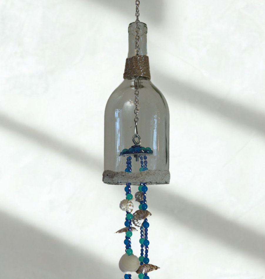 Decorative hanging with glass bottle wind chime, shells and beads on a white background