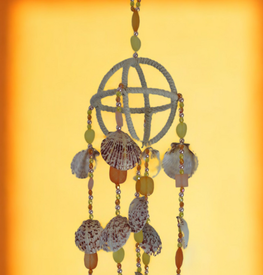 Decorative hanging wind chime with shells and beads on a yellow background