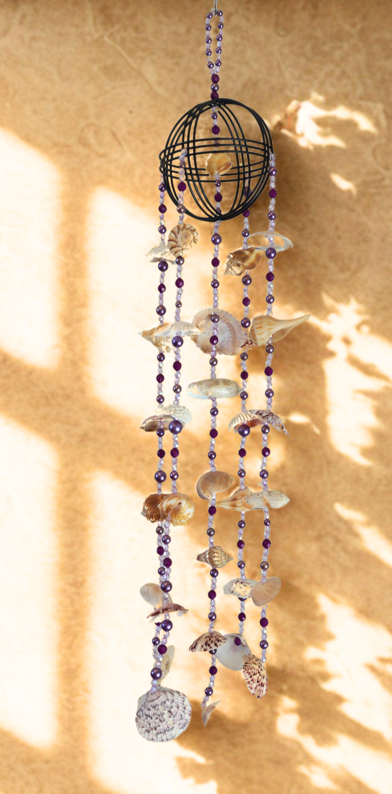 Decorative wind chime with seashells and beads on a beige background