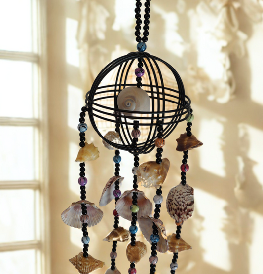 Decorative wind chime hanging with shells and beads against a neutral background