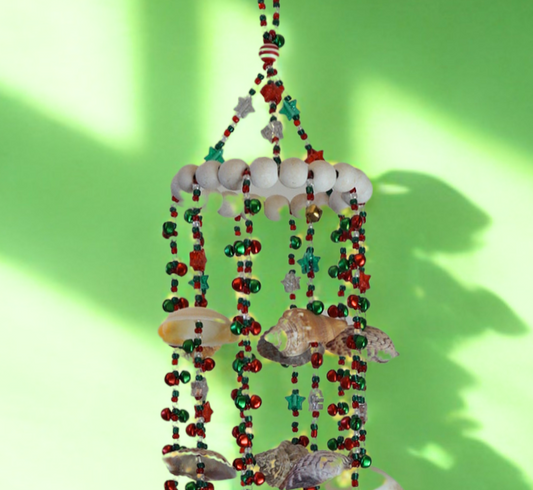 Decorative wind chime with colorful beads and shells on a green background