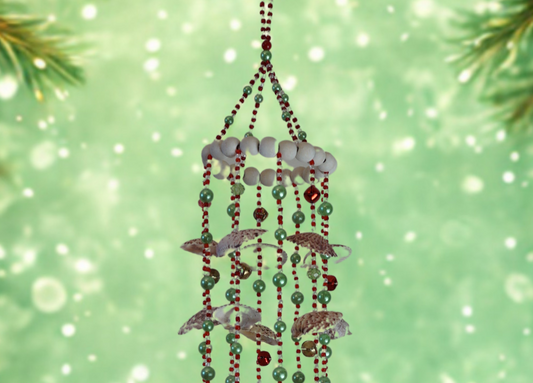 Decorative hanging wind chime with beads and shells against a festive green background.