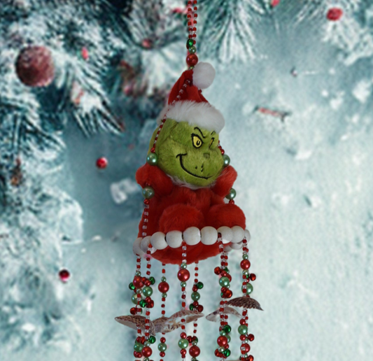 Decorative wind chime with shells resembling a character with a Santa hat, hanging against a snowy background.