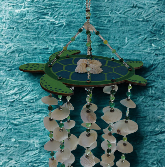Turtle-shaped wind chime with seashells and beads on a textured blue background