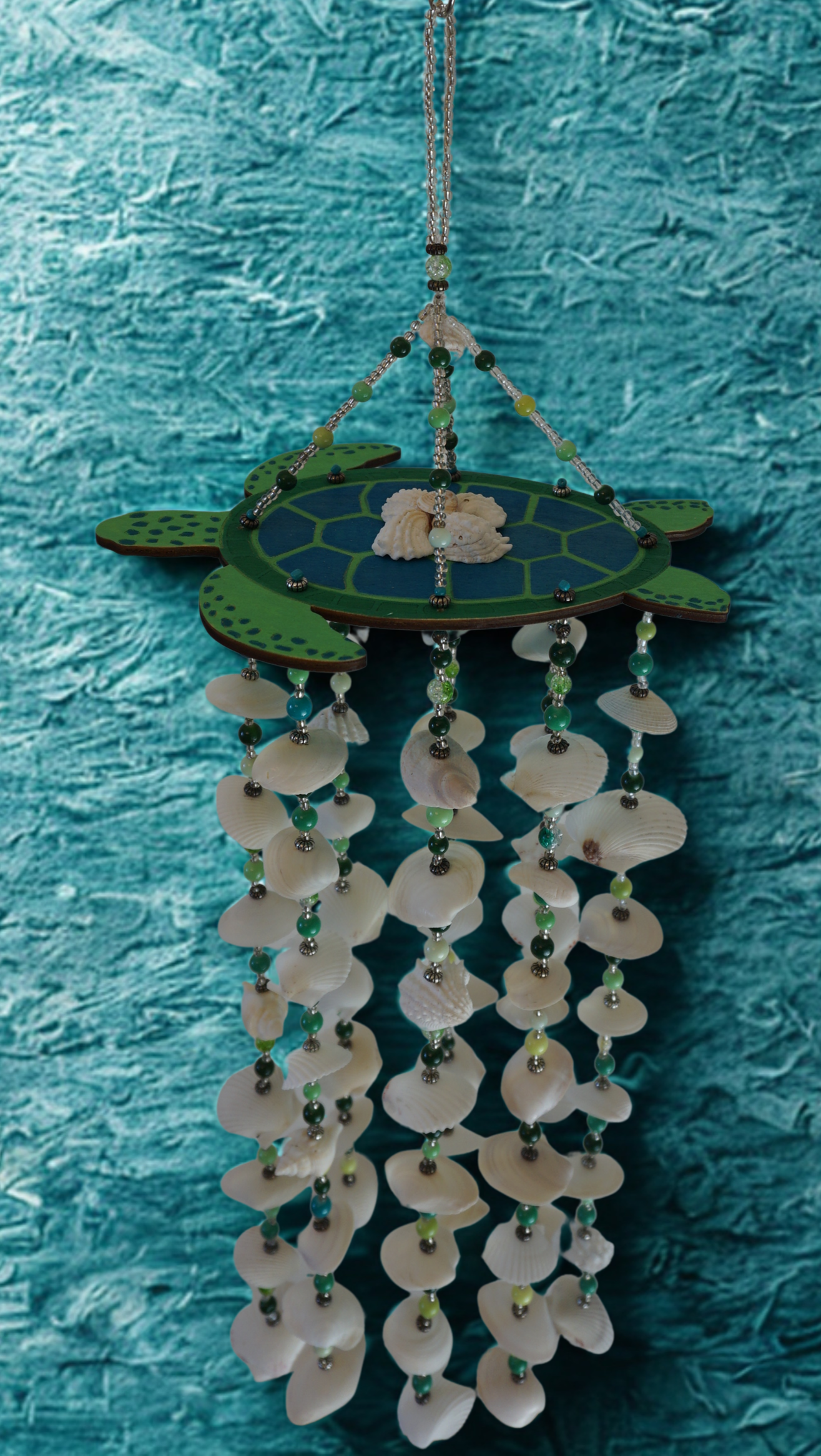 Decorative wind chime shaped like a turtle with shell elements on a textured blue background