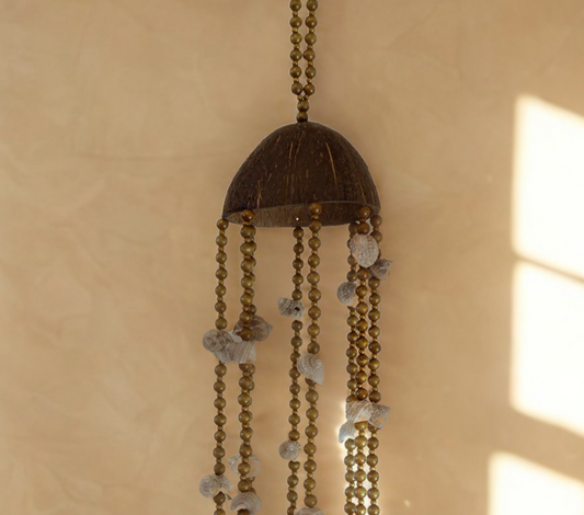 Coconut and shell wind chime hanging on a beige wall
