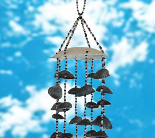 Wind chime with black shells against a blue sky with white clouds