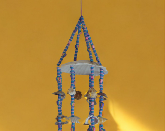 Decorative scallop shell top wind chime with colorful beads and shells on a yellow background